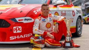 a man sitting on the ground next to a trophy